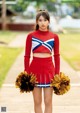 A young woman in a cheerleading uniform holding pom poms.