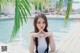 A woman in a white bathing suit posing by a pool.