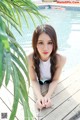 A woman sitting on a wooden deck next to a swimming pool.