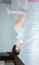 A woman laying on top of a bed in a white dress.