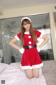 A woman in a santa claus outfit posing on a bed.