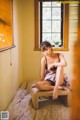 A woman sitting on a bed in front of a window.