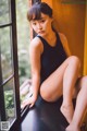 A woman in a black bathing suit sitting on a window sill.