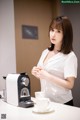 A woman standing in front of a coffee machine.