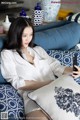 A woman sitting on a blue couch holding a cell phone.