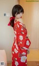 A woman in a red kimono standing in a room.