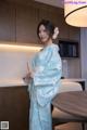 A woman in a blue and white kimono standing in a kitchen.