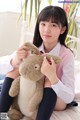 A young girl sitting on a bed holding a stuffed animal.