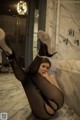 A woman in black stockings and high heels sitting on a marble floor.