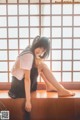 A woman sitting on a window sill with her legs crossed.